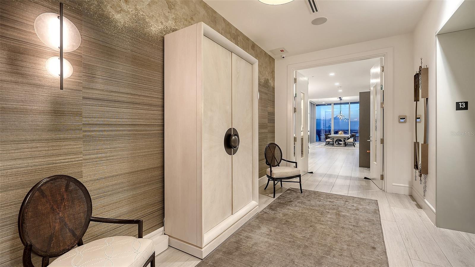 Condominium entry foyer with built-in cabinetry, accent chairs, and a distant water view.