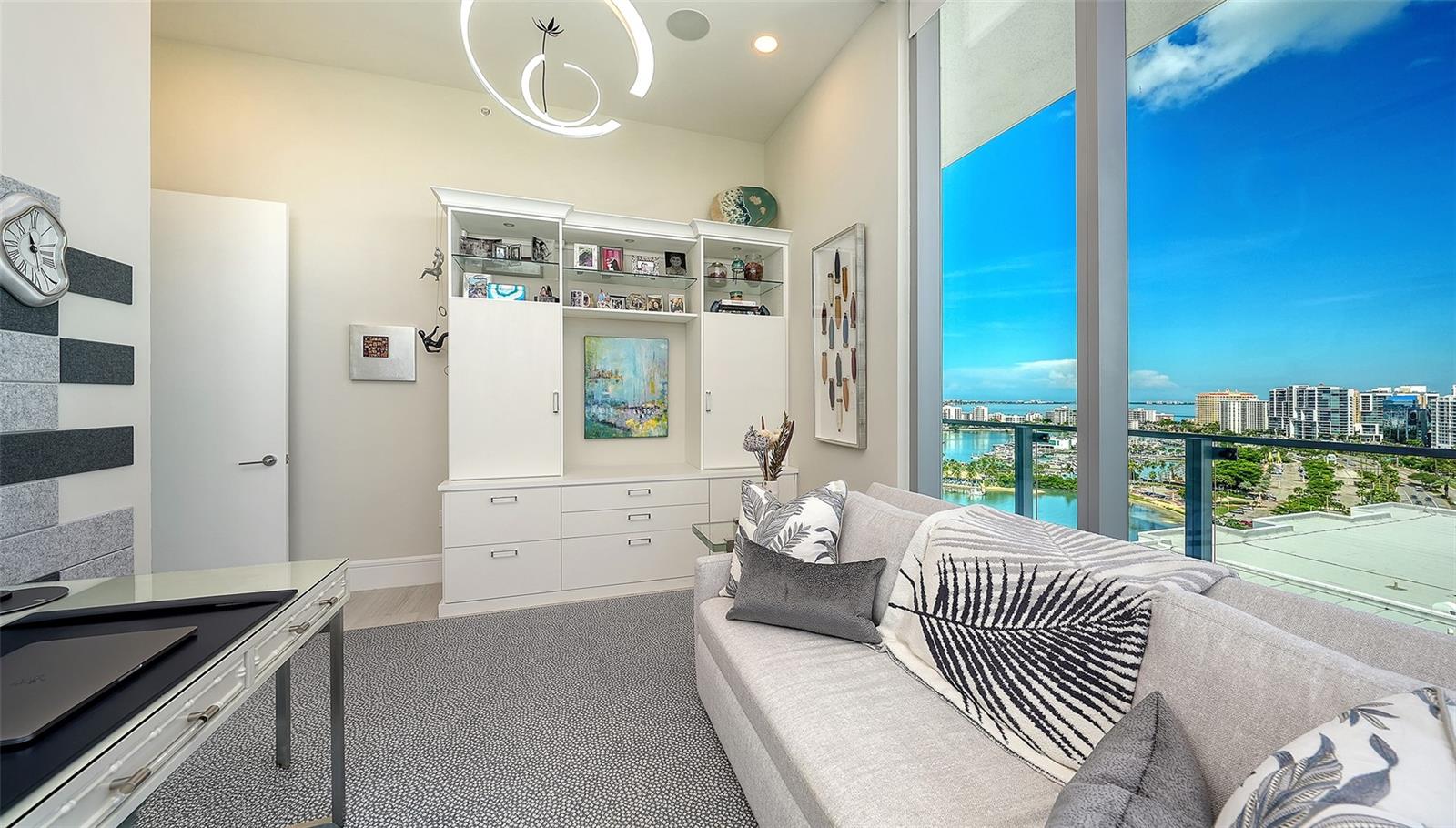 Condo living room with built-in cabinetry and floor-to-ceiling windows overlooking Sarasota Bay.