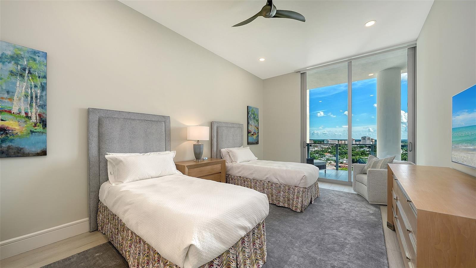 Bedroom with two twin beds and sliding glass doors overlooking the city and water.