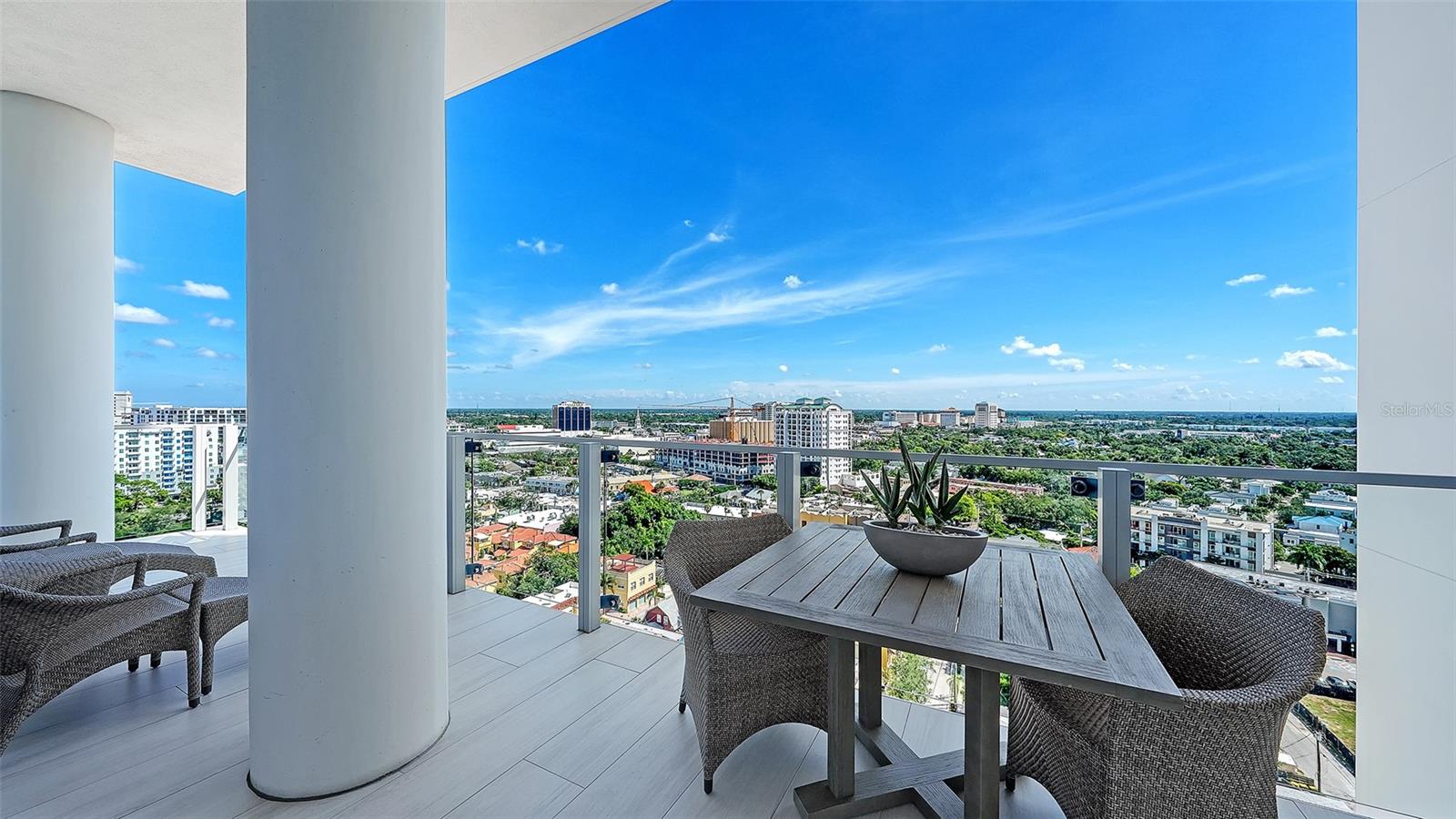 High-rise balcony dining area with wicker furniture overlooking the Sarasota cityscape.