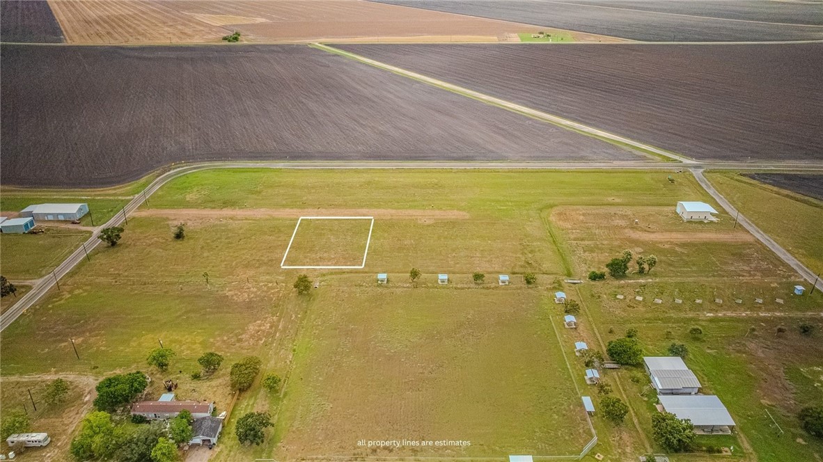 Aerial view of an outlined rural parcel amid farmland, scattered trees, and outbuildings.