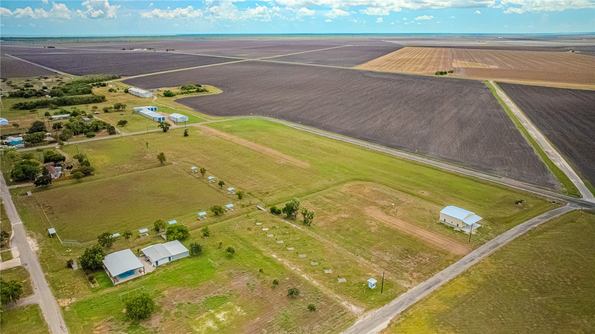 Rural acreage with scattered buildings, grassy open land, and expansive cultivated fields.