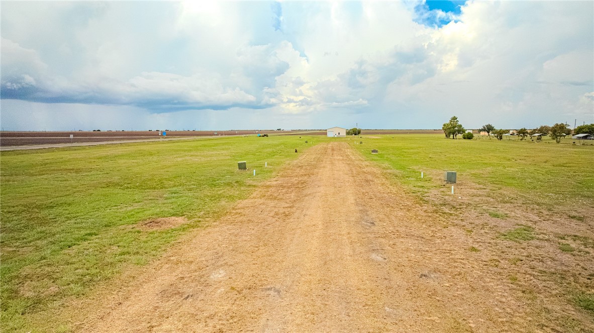 Open grassy property with a dirt track leading to a small building.