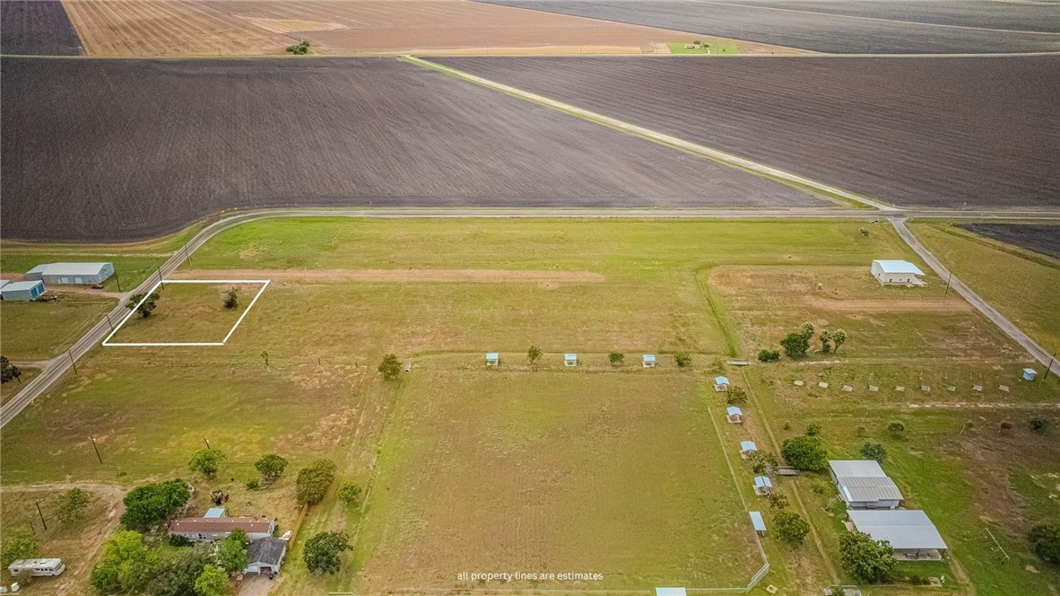 Aerial view of rural land with an outlined parcel, grassy fields, farm buildings, and surrounding cropland.