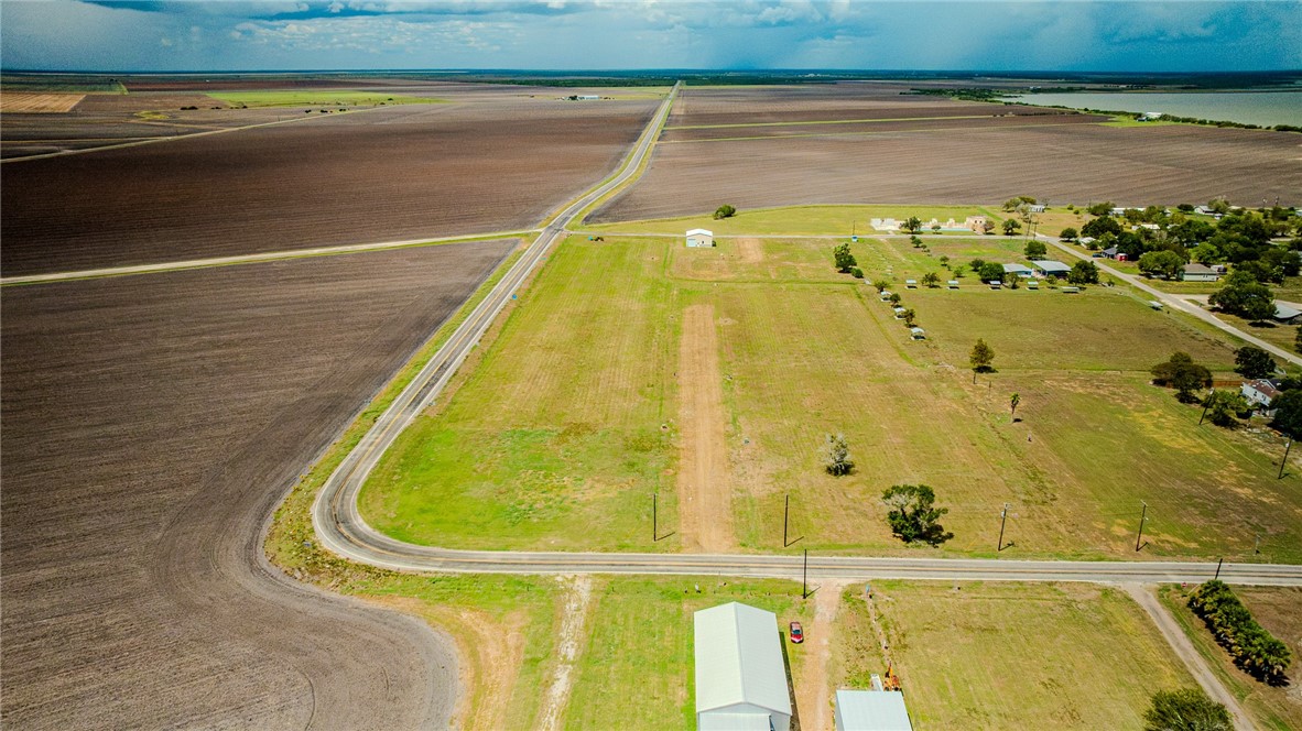 Rural acreage bordered by cultivated fields, with a paved road and several outbuildings.