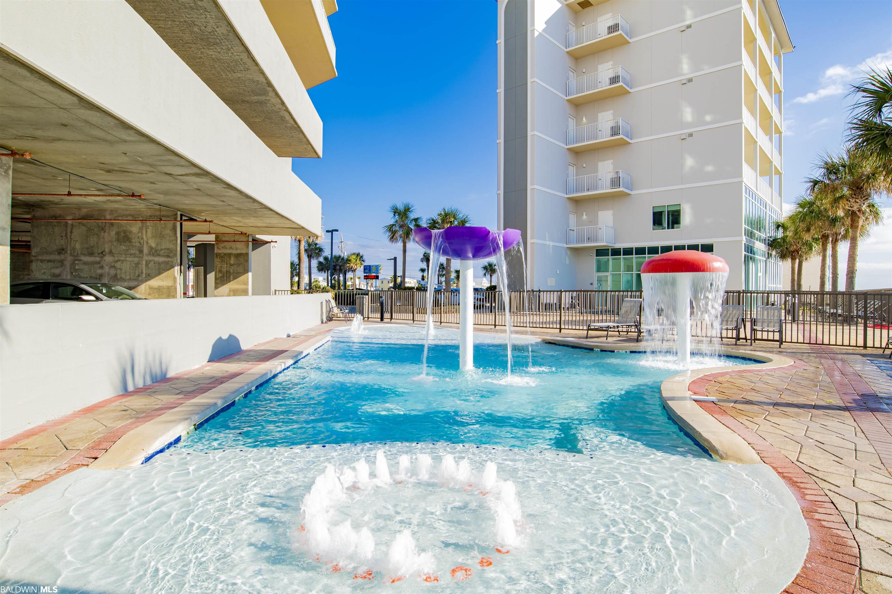 Condominium pool with a shallow splash area and colorful mushroom-shaped water fountains.