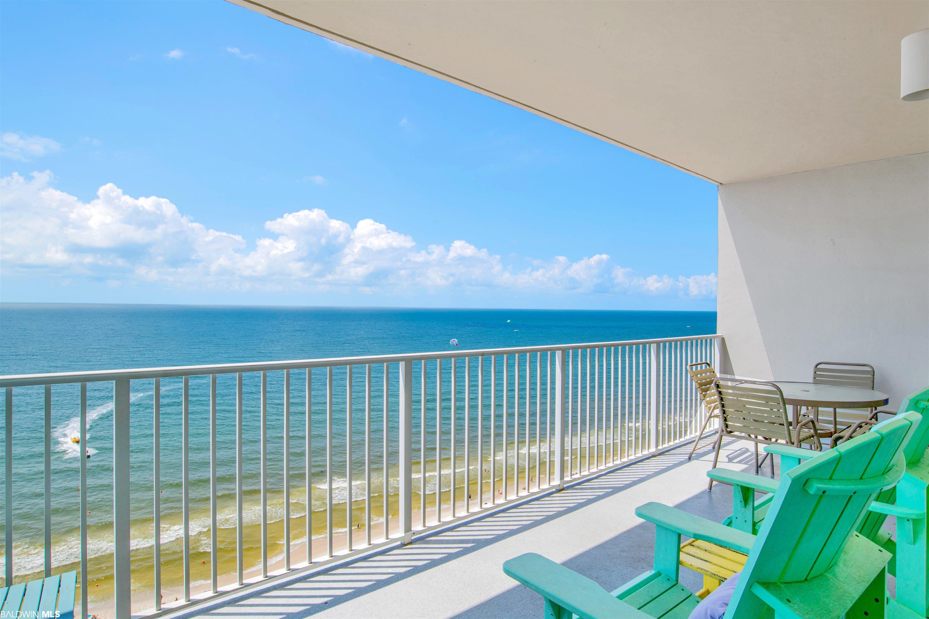 Furnished balcony overlooking the Gulf, with turquoise chairs and a beach view.