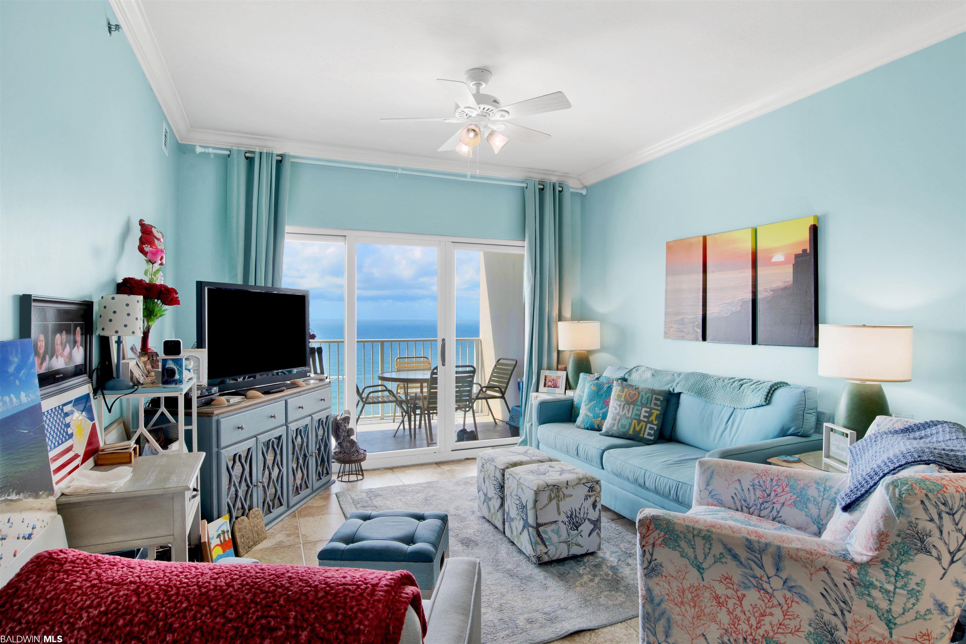 Furnished living room with blue seating and ocean views through sliding balcony doors.