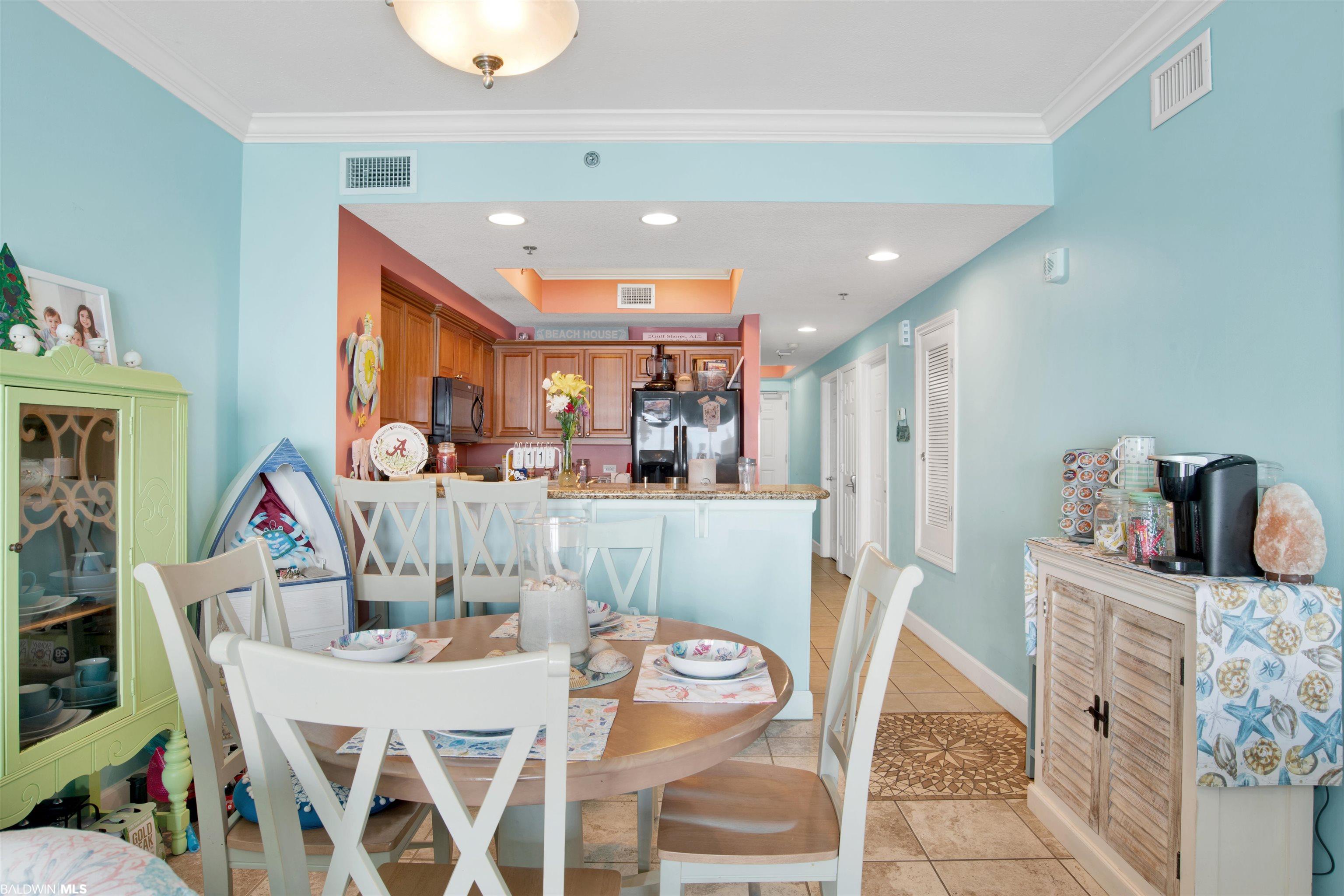 Dining area with a round table and white chairs opening into a wood-cabinet kitchen.