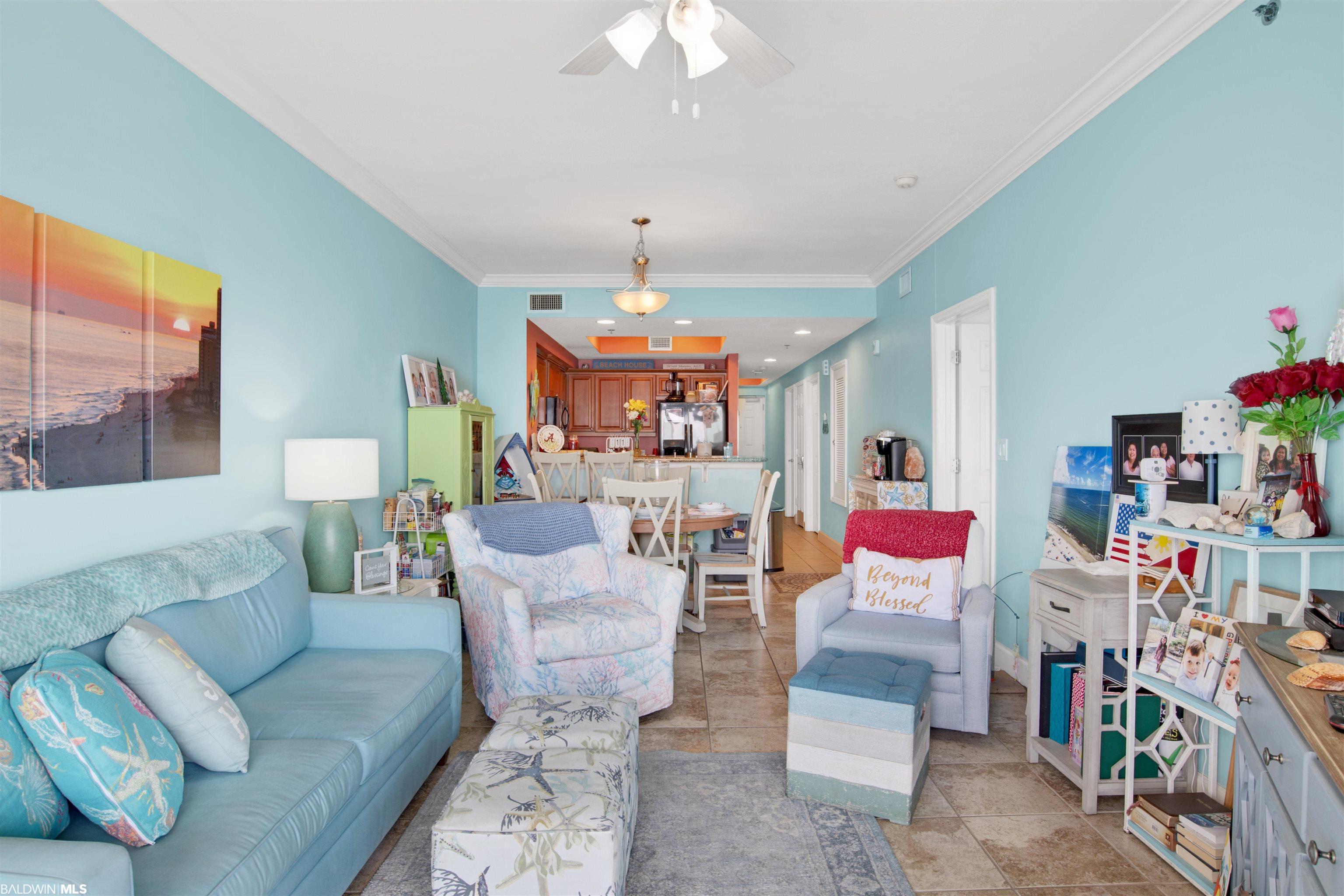 Furnished aqua living room with blue sofa and open dining area leading to the kitchen.