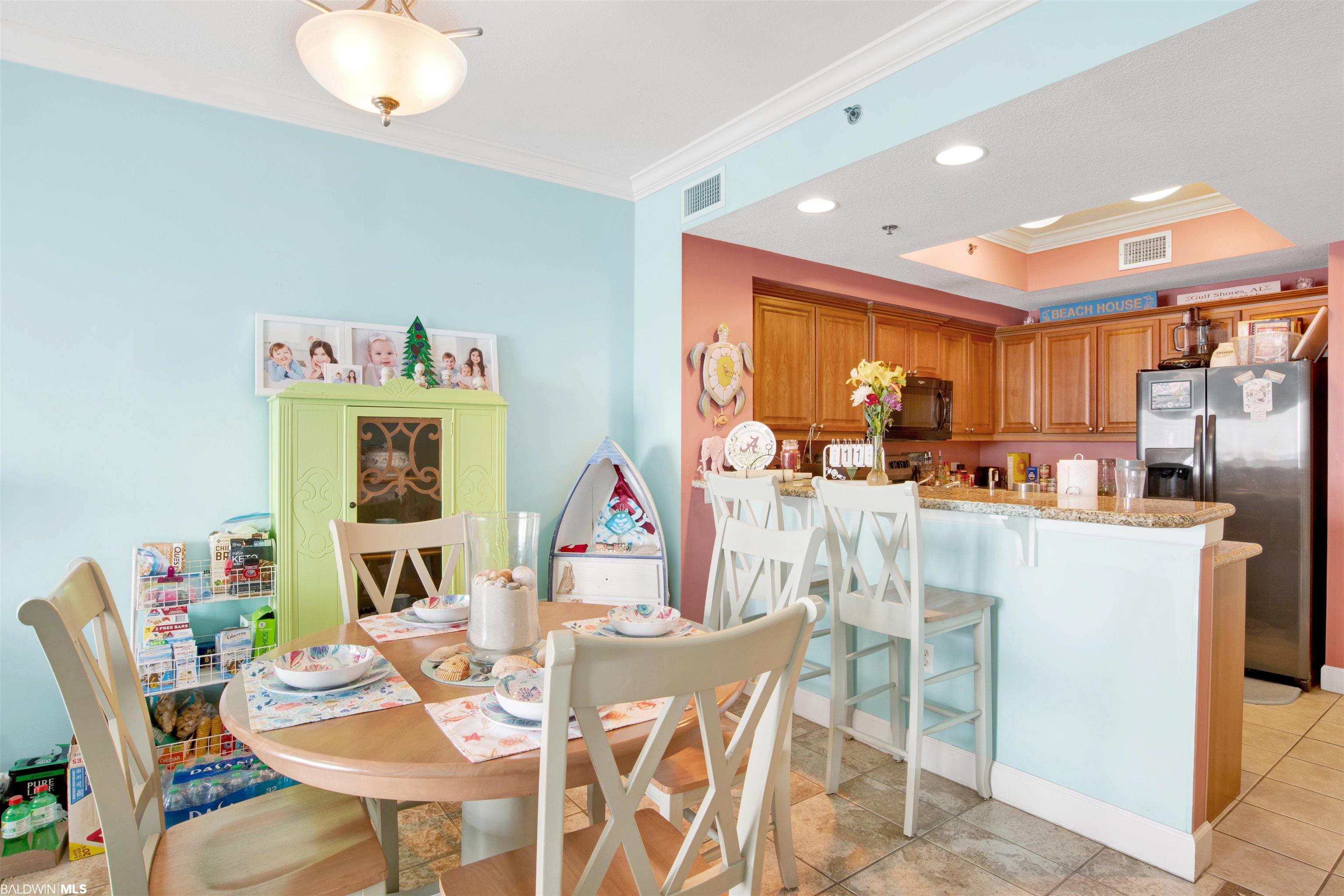 Condo kitchen and dining area with a breakfast bar, wood cabinets, and a set table.