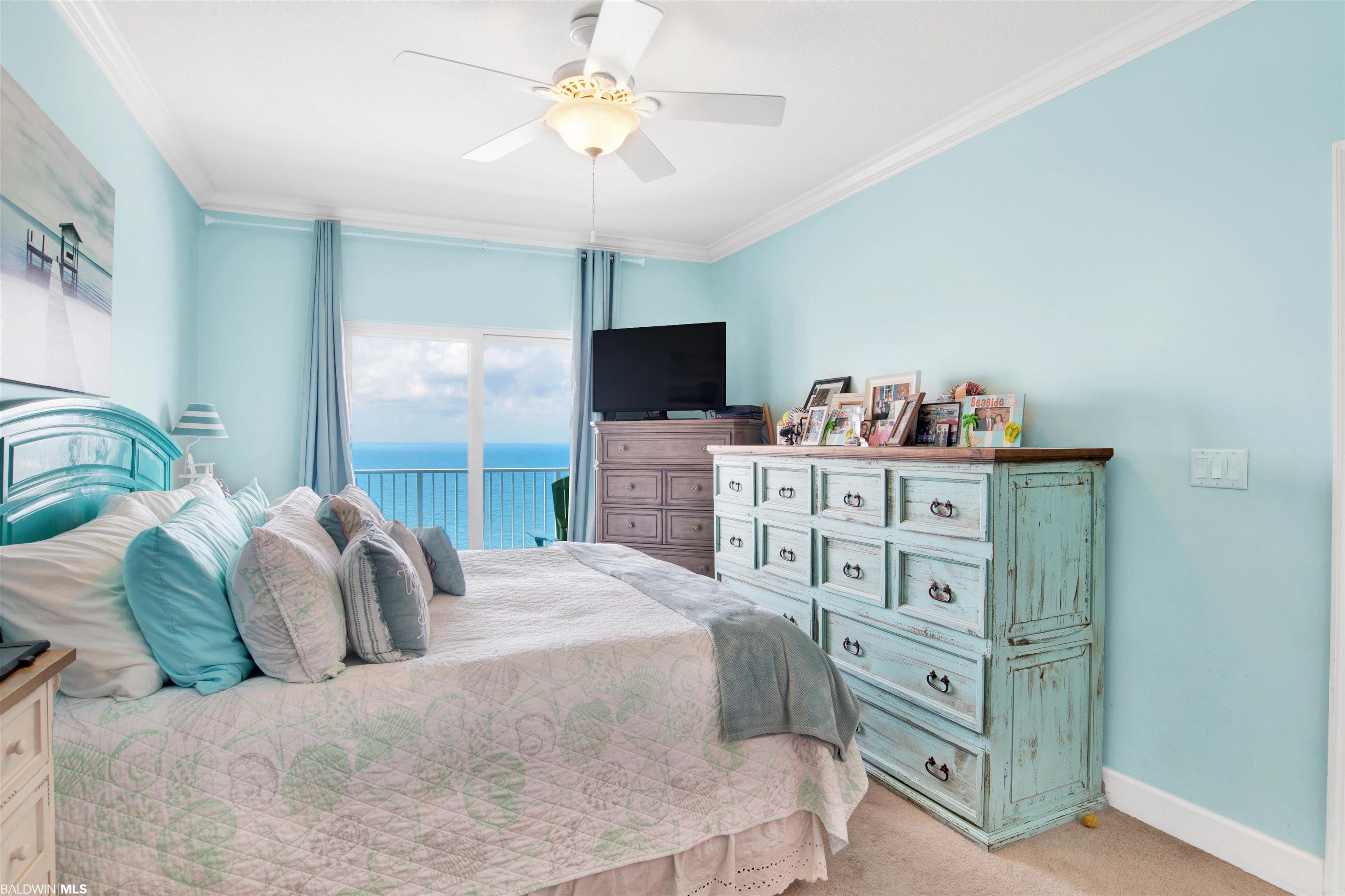 Coastal bedroom with aqua walls, a turquoise dresser, and ocean views through the balcony doors.