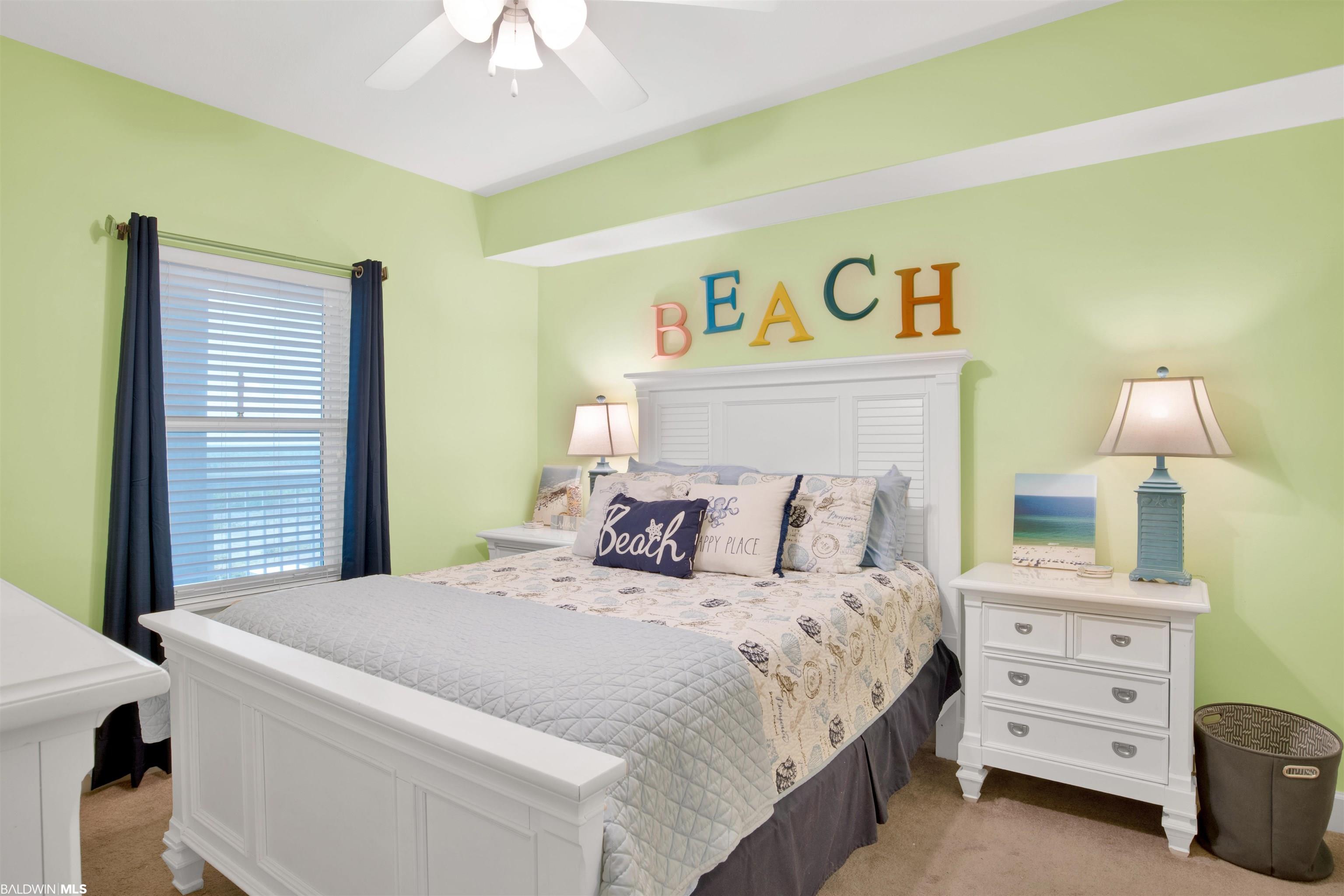 Beach-themed bedroom with a white bed, shell-patterned bedding, and colorful BEACH letters above the headboard.