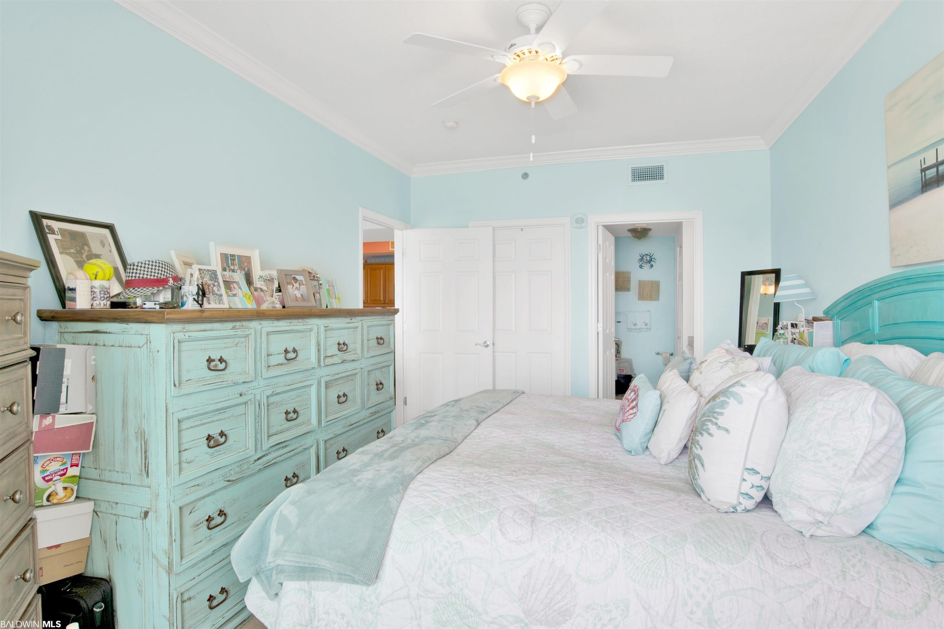 Bedroom with aqua walls, turquoise headboard, white bedding, and a distressed aqua dresser.