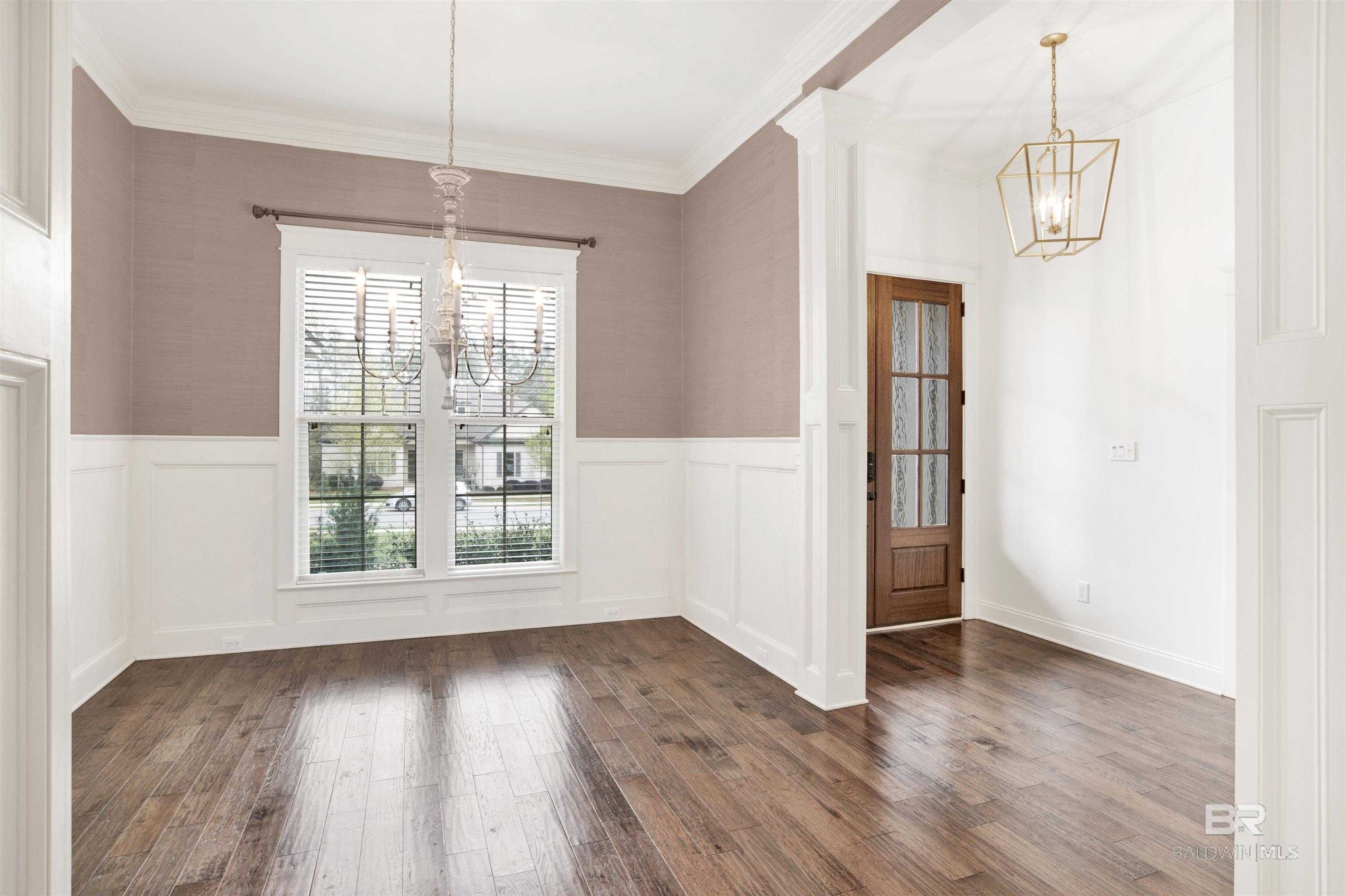 Unfurnished dining room with a chandelier, tall shuttered windows, and wood-look flooring.
