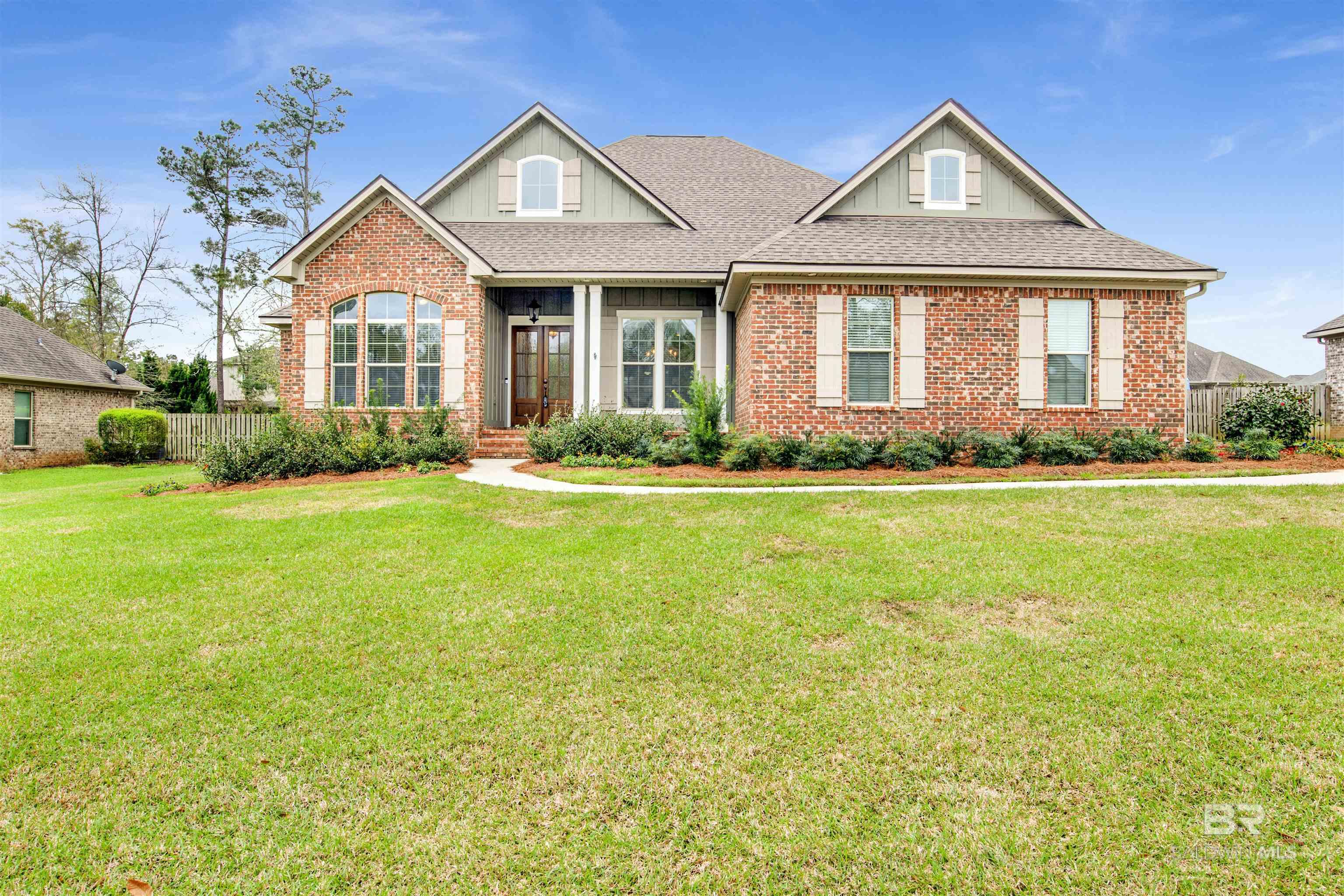 Brick-front house with a broad lawn, landscaped beds, and a covered entry.