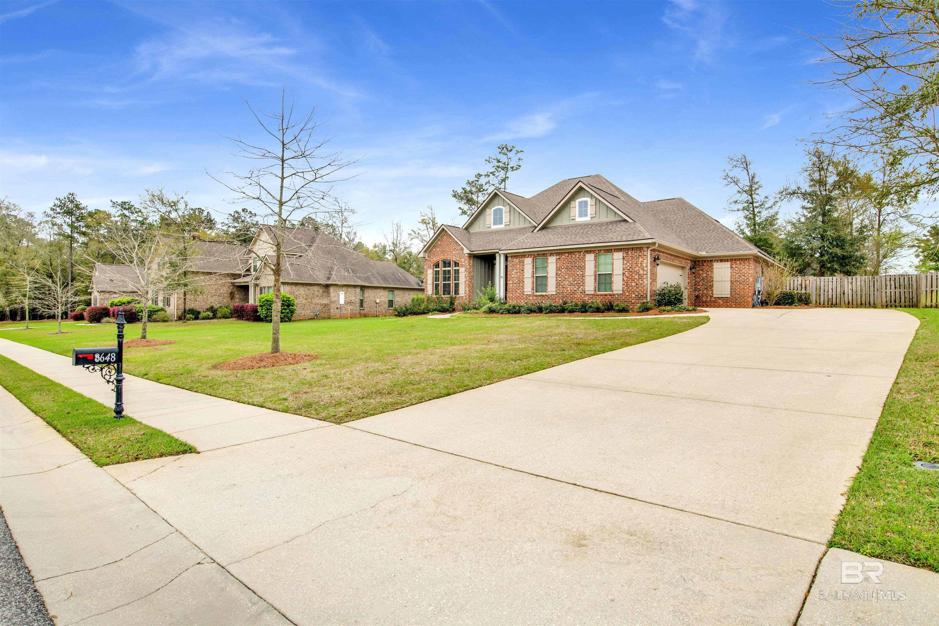 Red-brick home with a broad curved driveway, front lawn, and mailbox marked 8648.