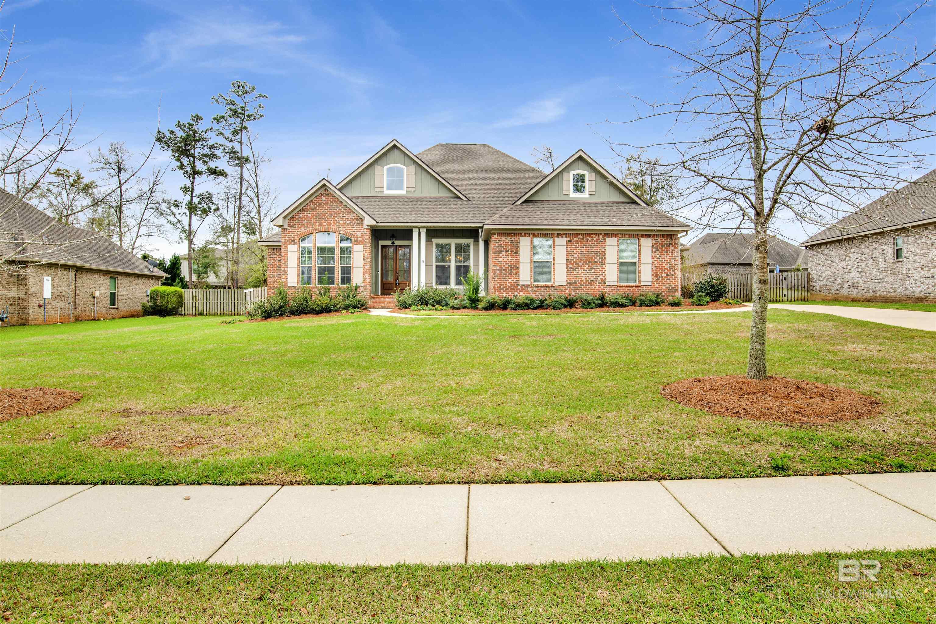 Red-brick home with multiple gables, a covered entry, and a broad front lawn.