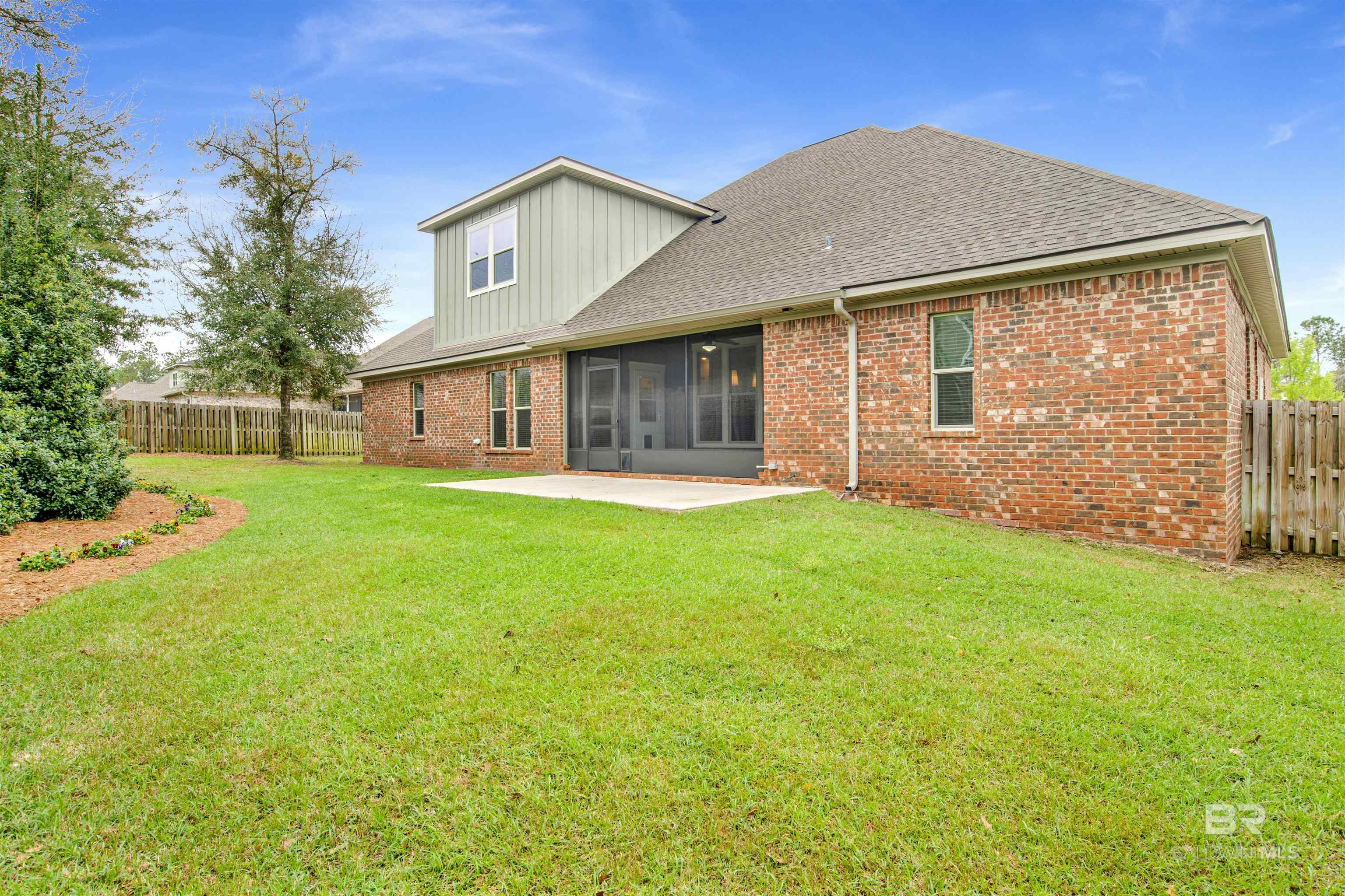 Brick house rear exterior with screened patio and broad lawn.