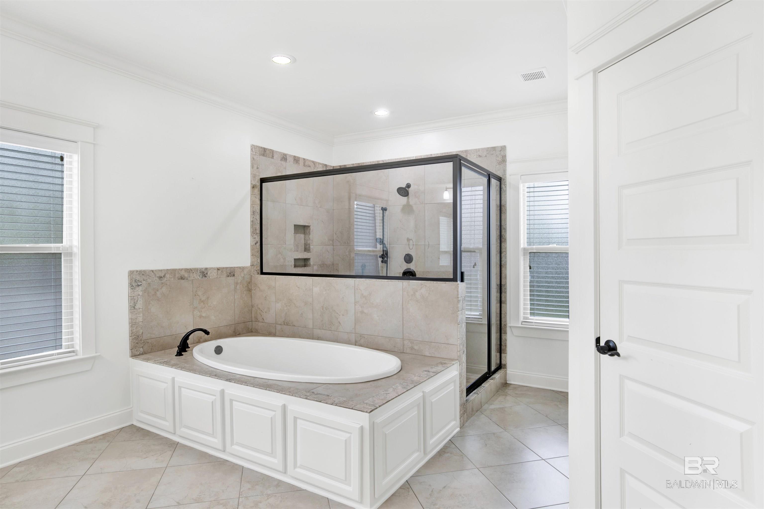 Bathroom with a built-in soaking tub beside a large glass-enclosed tiled shower.