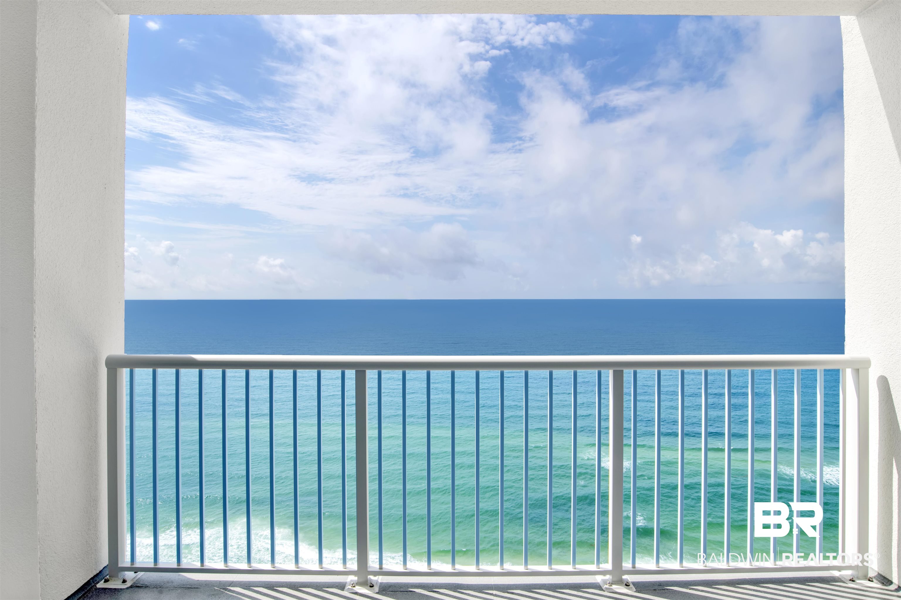 Gulf water and horizon viewed from a balcony with a white metal railing.