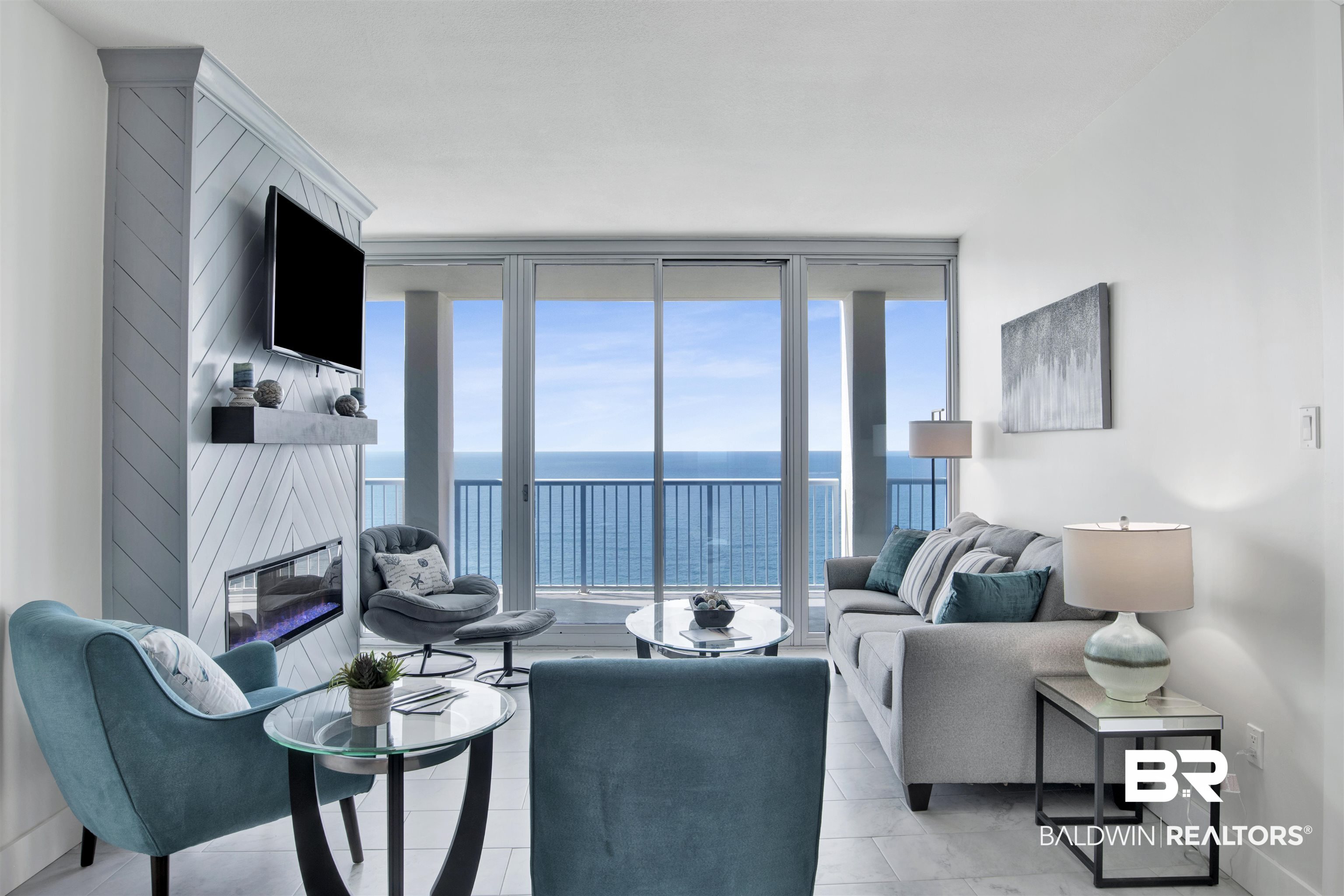 Furnished living room with teal accents and a balcony overlooking the ocean.