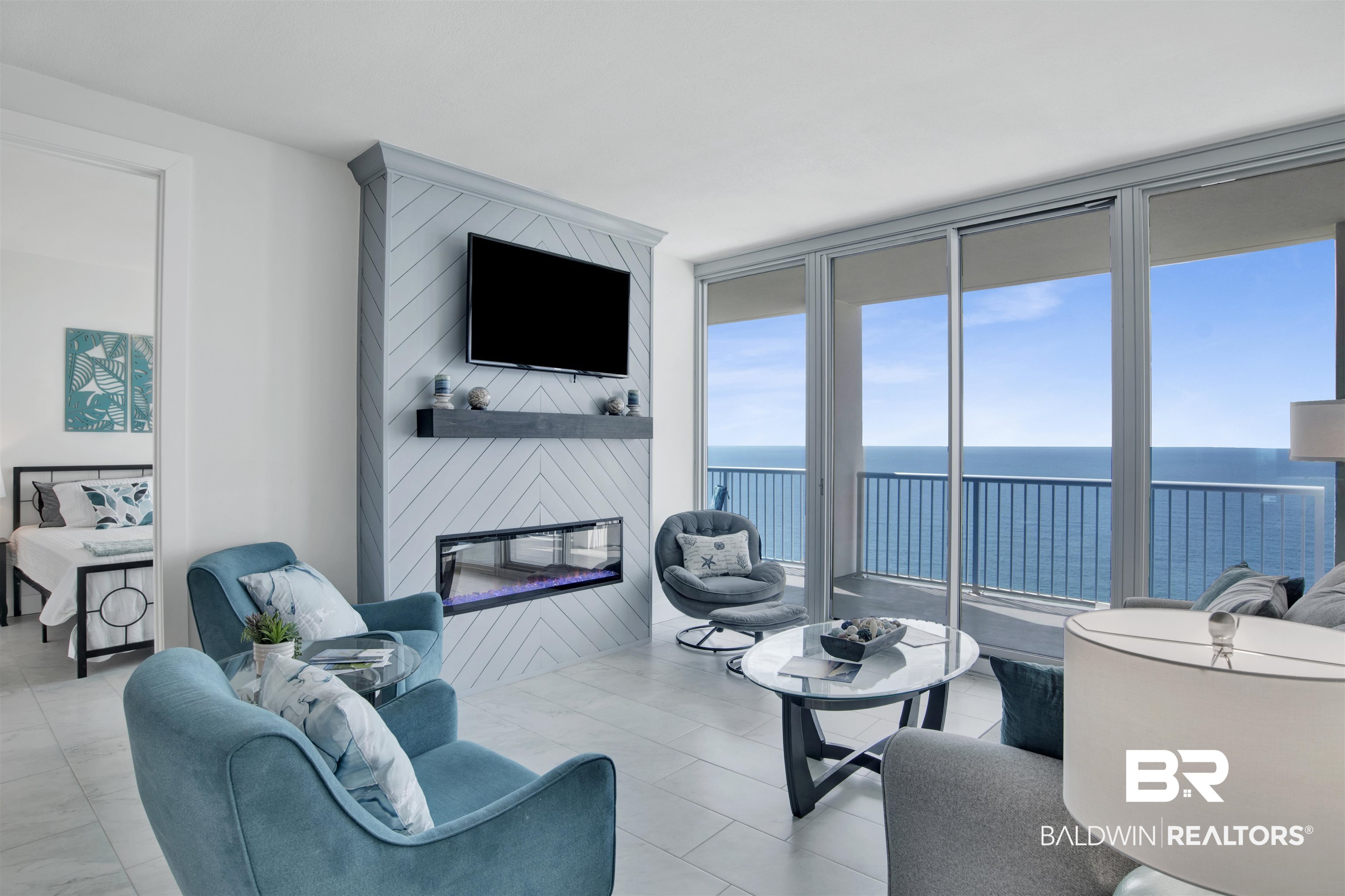 Furnished living room with a linear fireplace and sliding doors overlooking the ocean.