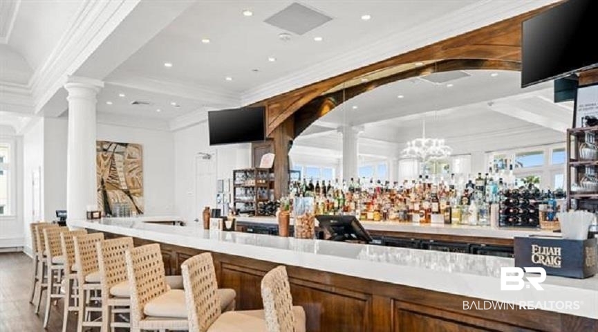 Bar with a white counter, woven stools, and mirrored shelves stocked with liquor bottles.