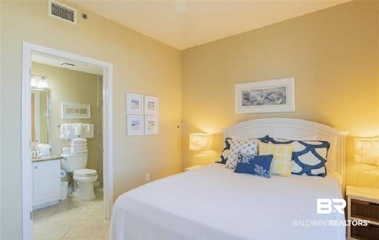 Bedroom with a white bed, navy and yellow pillows, and an open doorway to the en-suite bathroom.