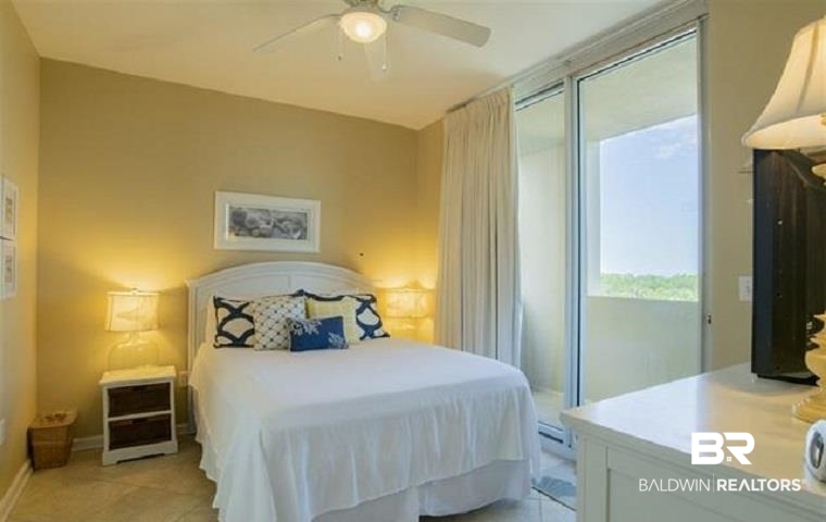 Bedroom with a white bed, matching bedside lamps, and sliding glass door to a balcony.