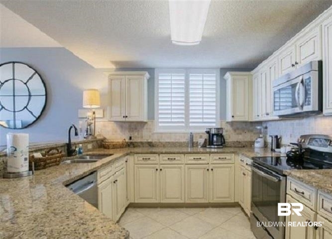 Condo kitchen with cream cabinets, granite countertops, and stainless steel appliances.