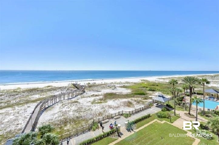 Beach and Gulf view with a boardwalk across the dunes, palm trees, and a swimming pool.