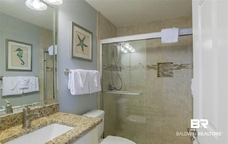 Bathroom with a glass shower enclosure, beige tile and granite vanity.