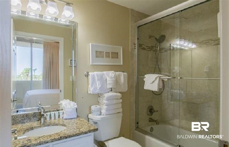 Bathroom with a glass-enclosed shower, granite vanity, and neatly folded white towels.
