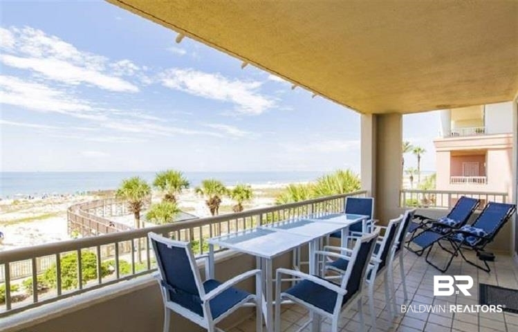 Condo balcony with blue chairs and a dining table overlooking the beach and Gulf.