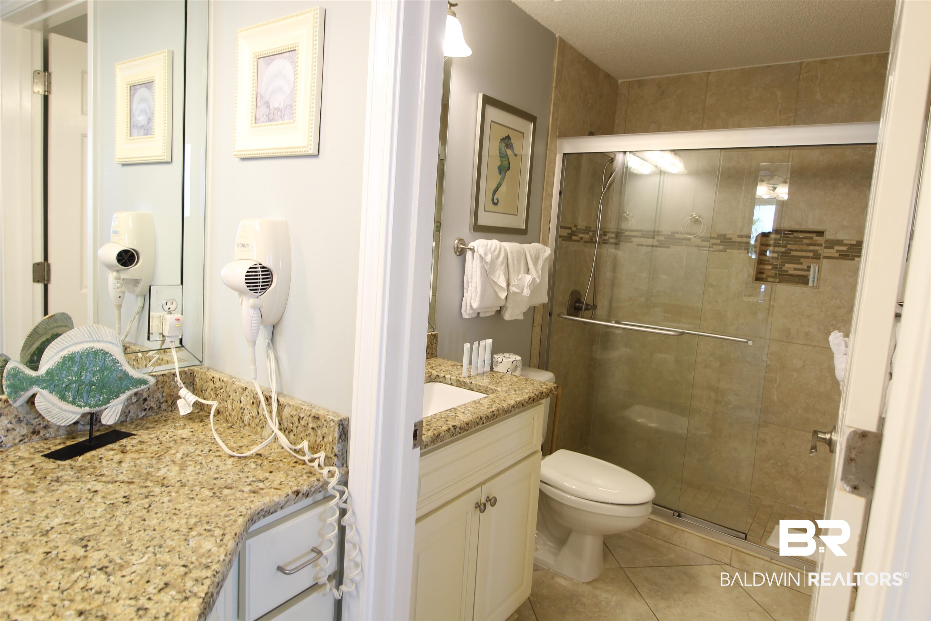 Bathroom with granite vanity and glass shower featuring tiled walls, a built-in niche, and grab bar.