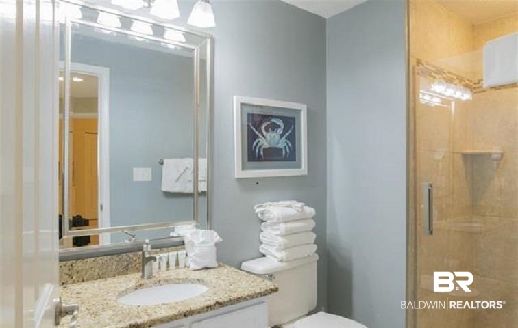 Bathroom with a granite vanity, framed crab artwork, and a glass-enclosed shower.