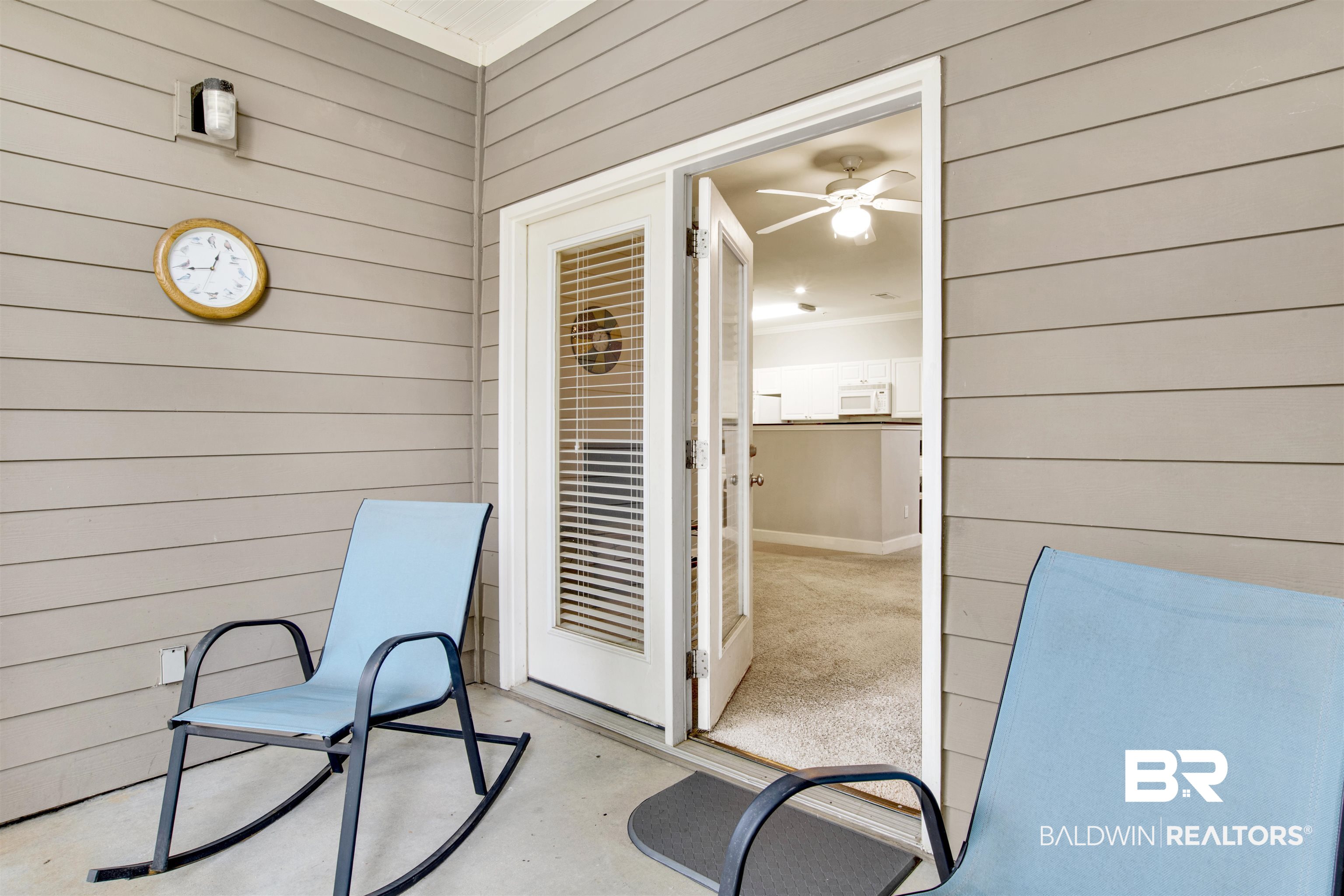 Covered patio with blue chairs and an open doorway revealing the kitchen.