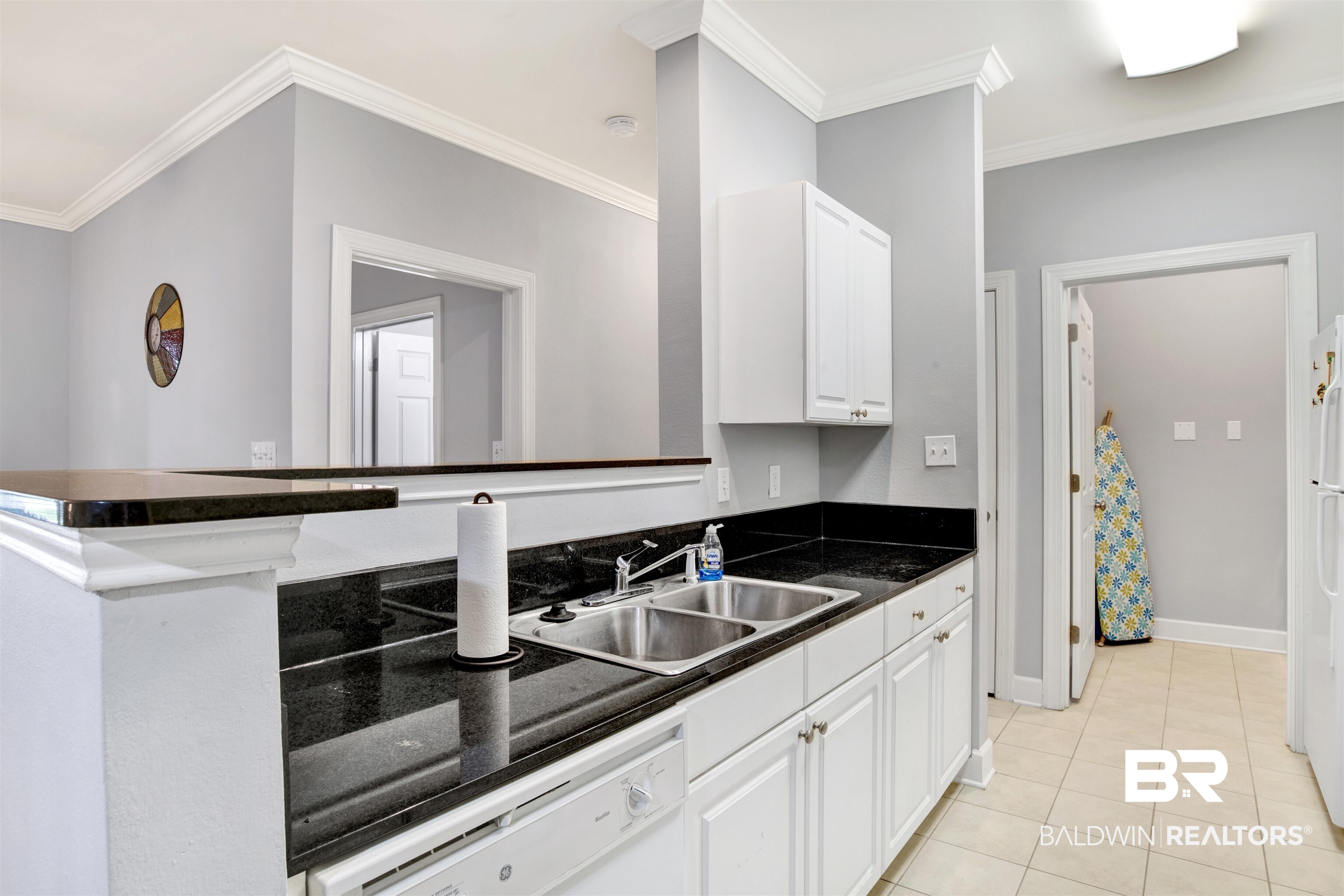 Kitchen with black granite countertops, white cabinets, and a stainless steel double-basin sink.
