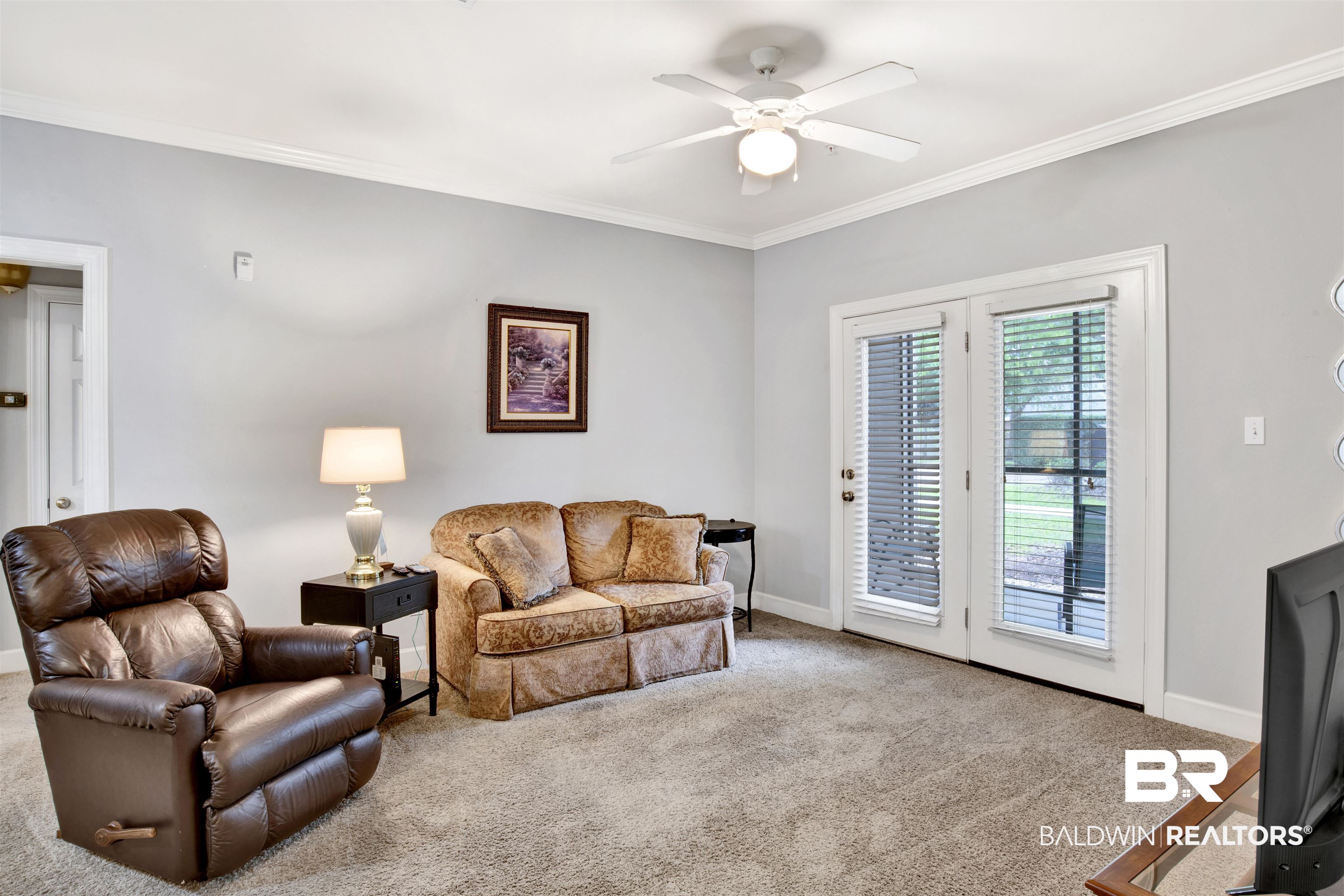 Living room with a brown leather recliner, patterned loveseat, and glass doors with blinds.