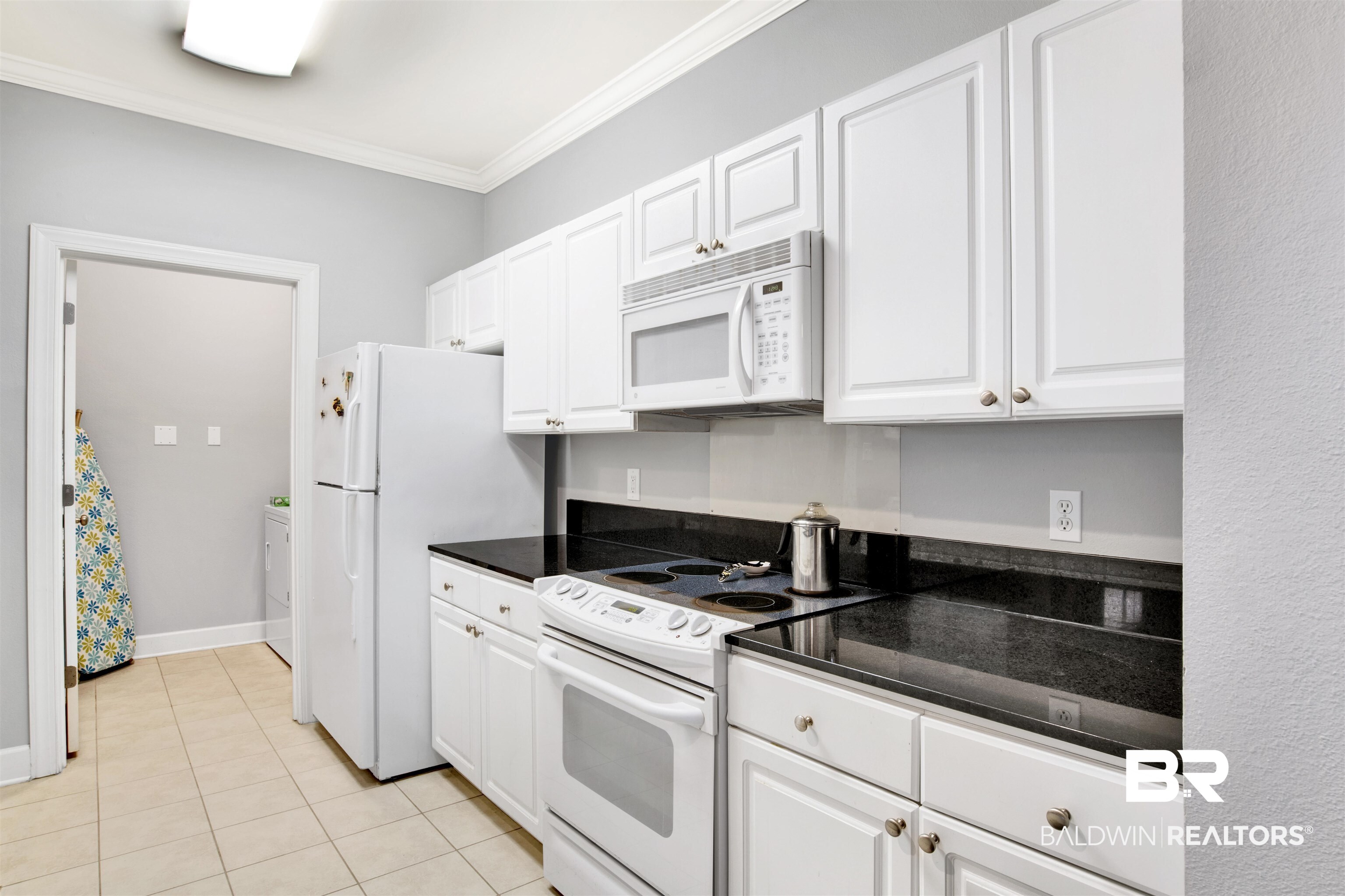 Kitchen with white cabinets, black countertops, and white appliances.