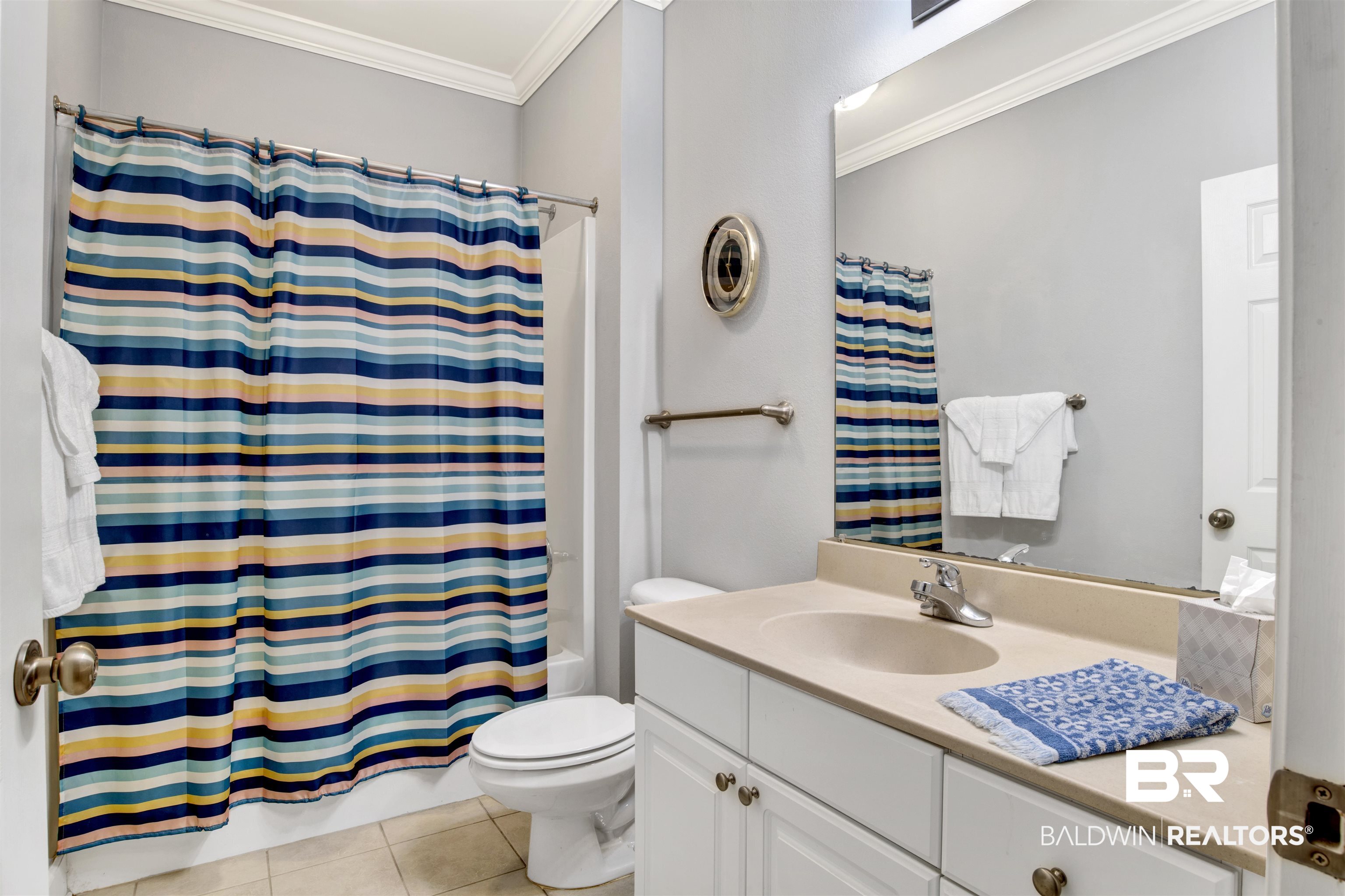 Bathroom with a white vanity, large mirror, and colorful striped shower curtain.