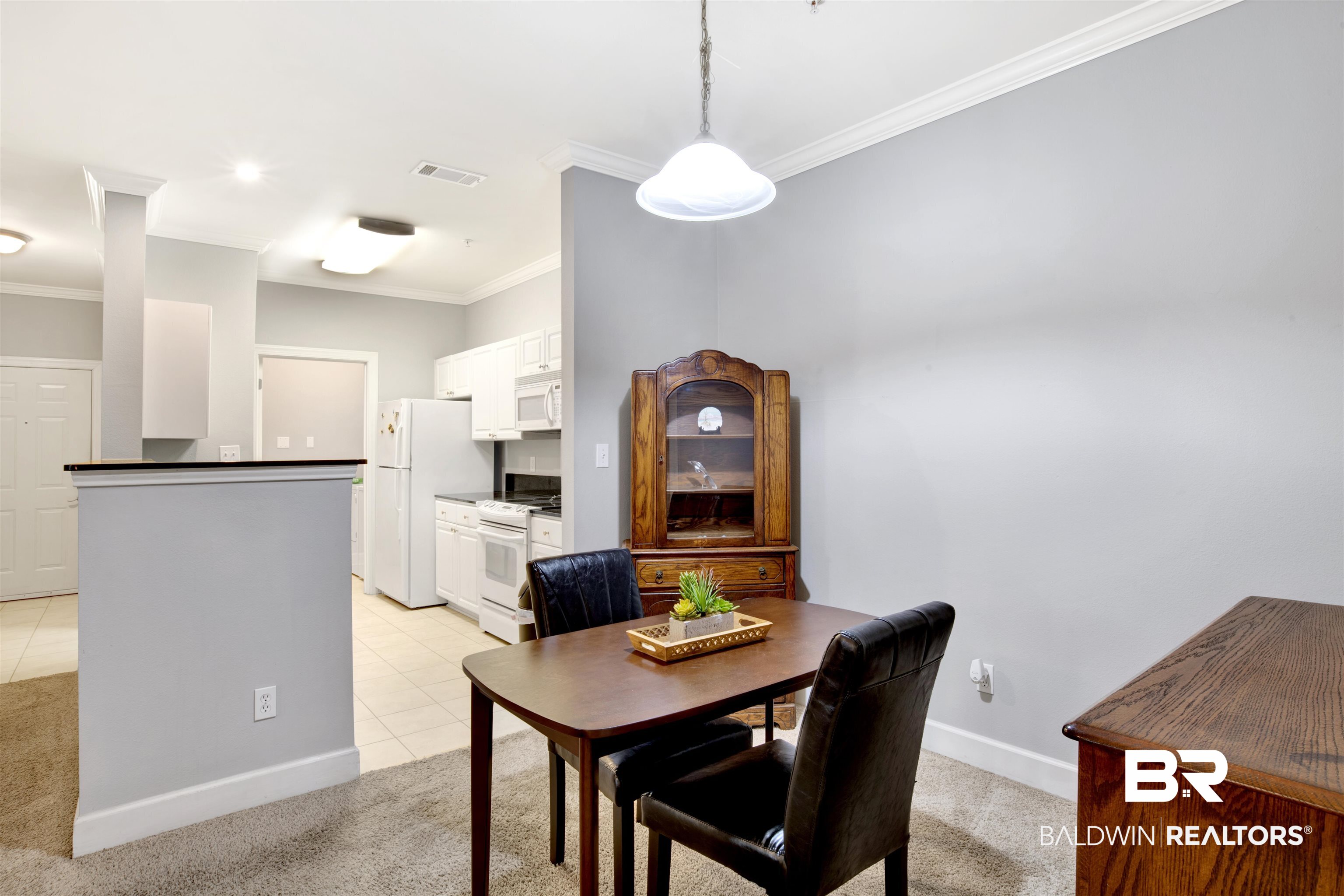 Dining area with a wooden table and china cabinet beside an open kitchen.