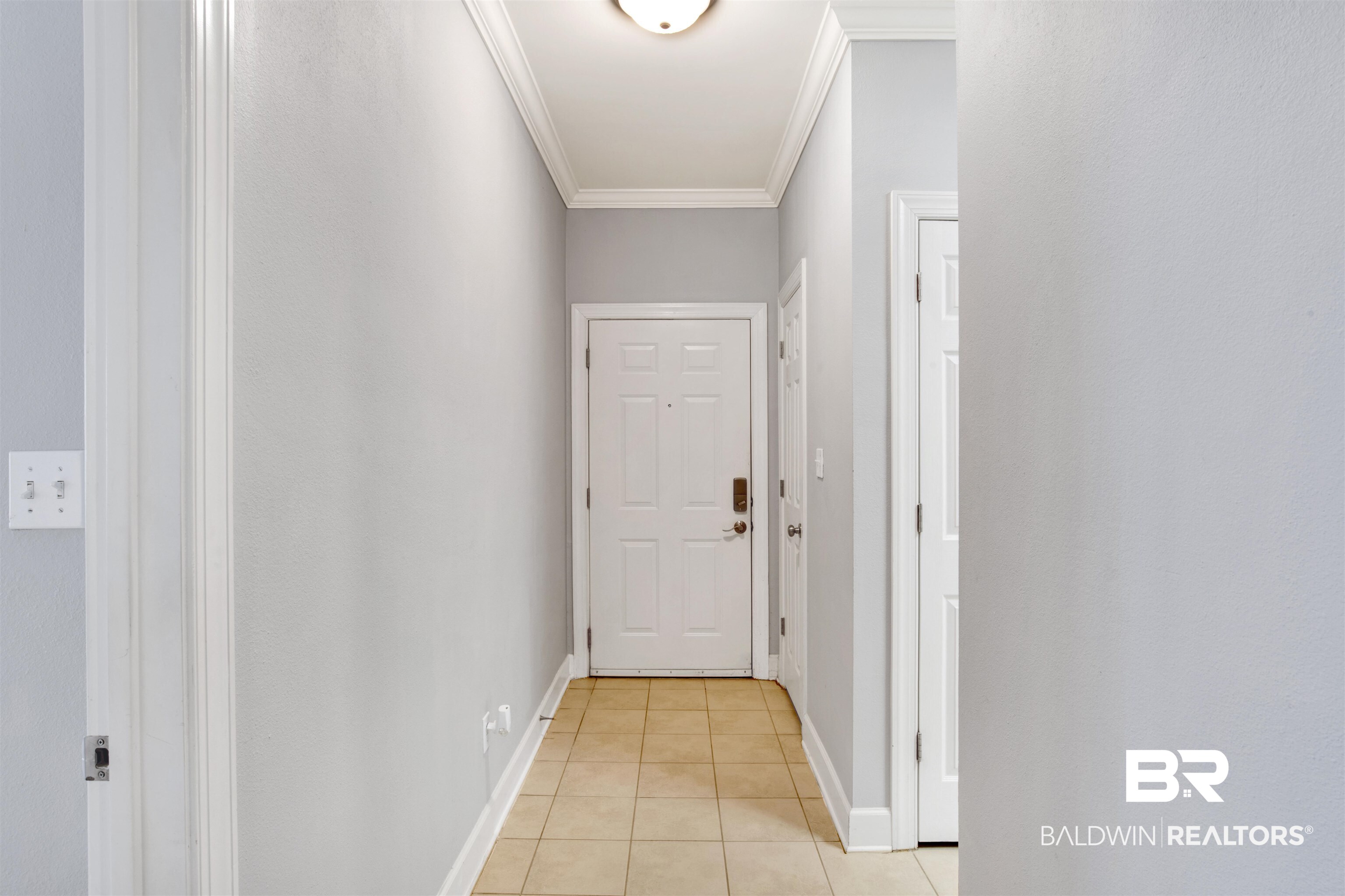 Entry hallway with beige tile flooring and a white paneled front door.