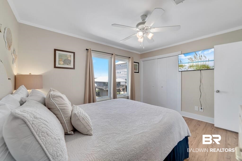 Bedroom with a large white bed, ceiling fan, and windows overlooking the water.