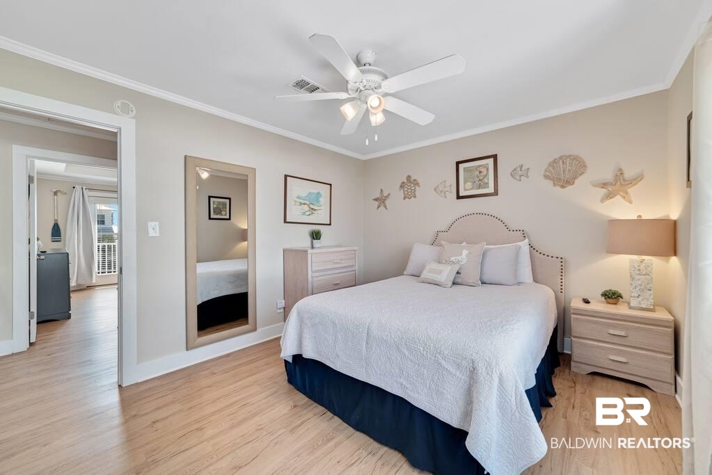 Bedroom with a white bed, coastal wall decorations, and pale wood flooring.