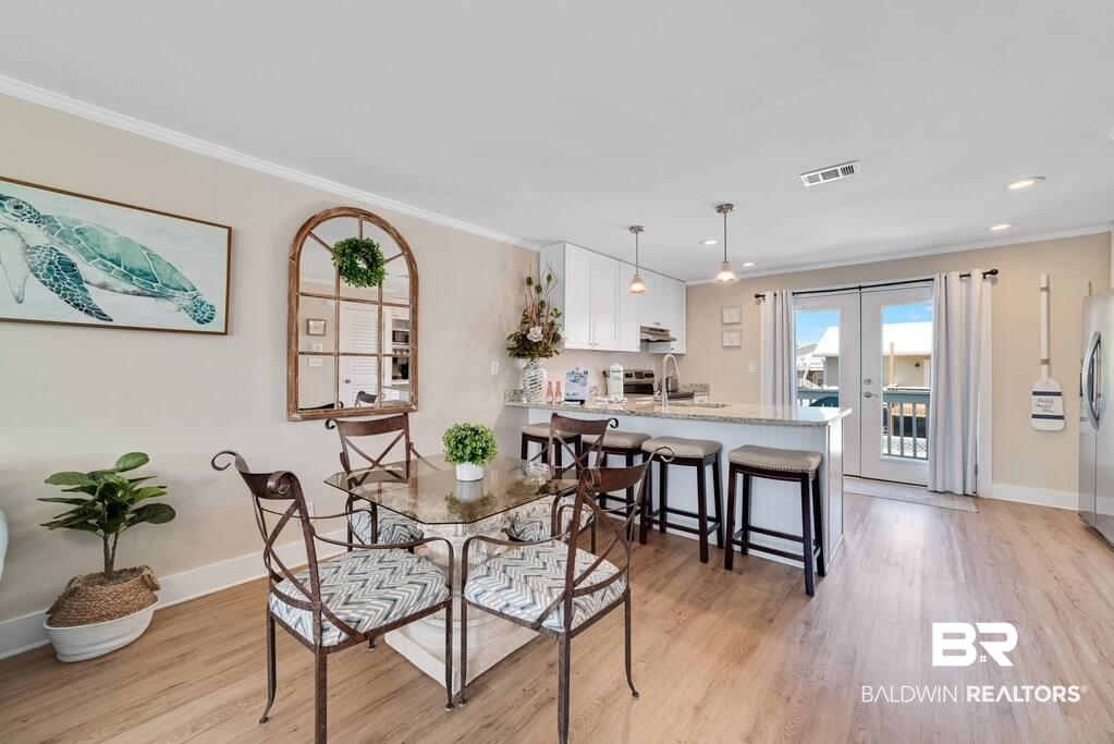 Dining area beside a white-cabinet kitchen, with a glass-top table and breakfast bar.