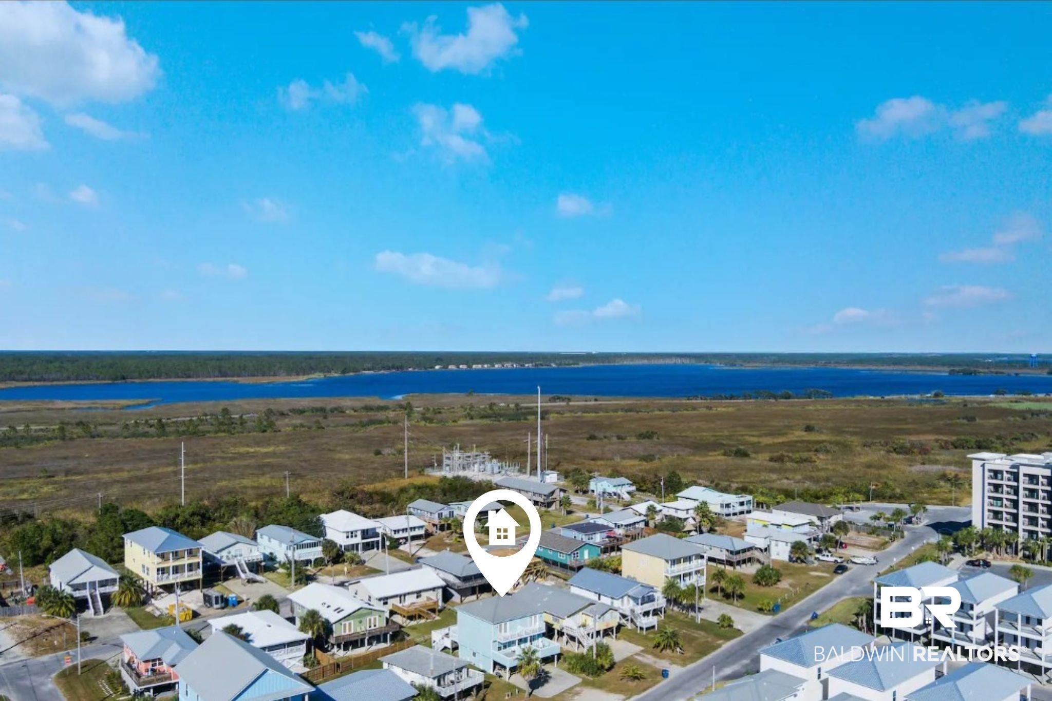 Aerial view of coastal homes beside wetlands and a blue waterway.