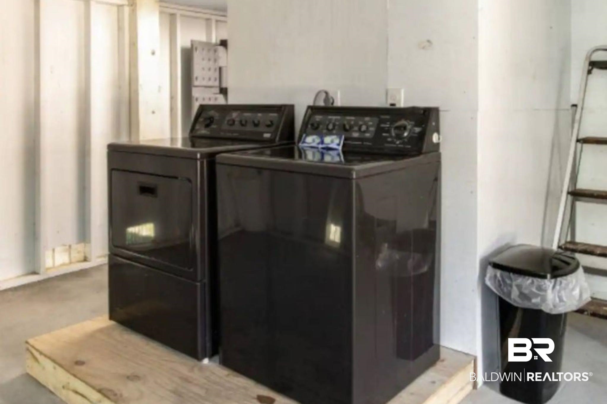 Laundry area with a black washer and dryer on a raised wooden platform.