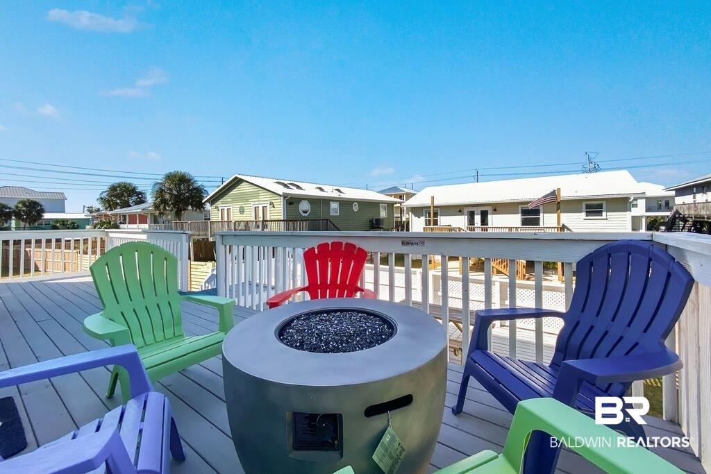 Outdoor deck with colorful Adirondack chairs surrounding a round fire pit.